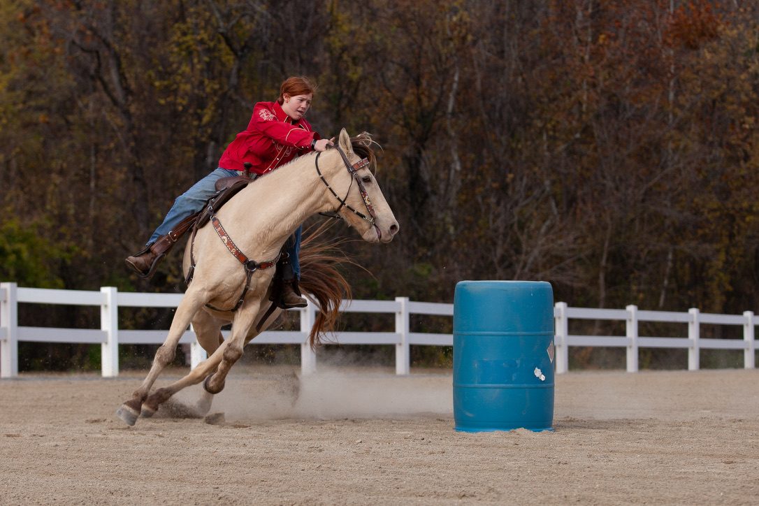 Rider in a red shirt turning a barrel at speed in the Harborwood arena